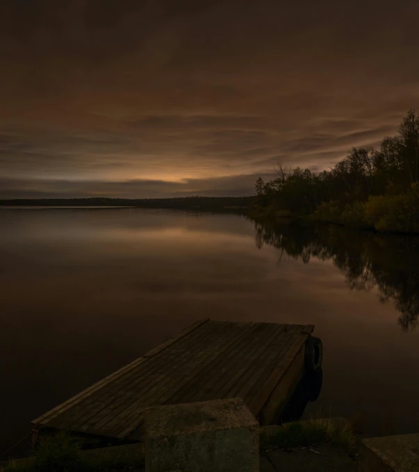 a dock sitting on top of a lake under a cloudy sky, by Jesper Myrfors, pexels contest winner, romanticism, dark golden light night, muted colours 8 k, brown, spring evening