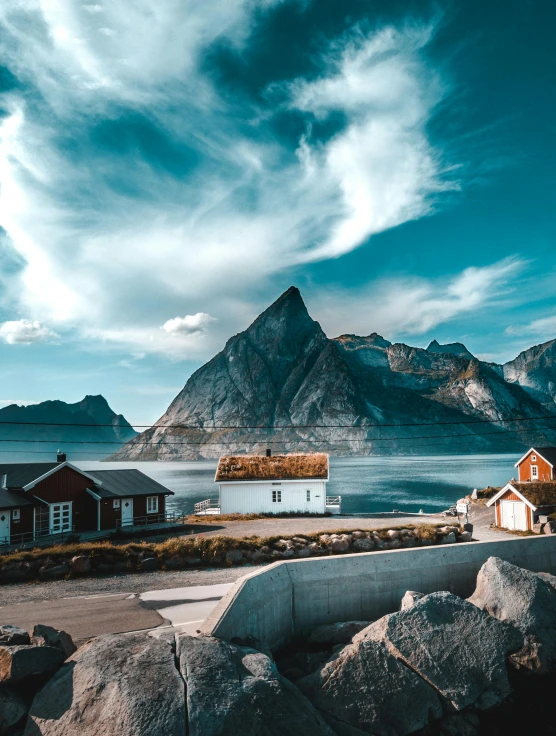 a red house sitting on top of a hill next to a body of water, by Sebastian Spreng, pexels contest winner, ice mountains in the background, several cottages, 4 k cinematic panoramic view, nostalgic vibes