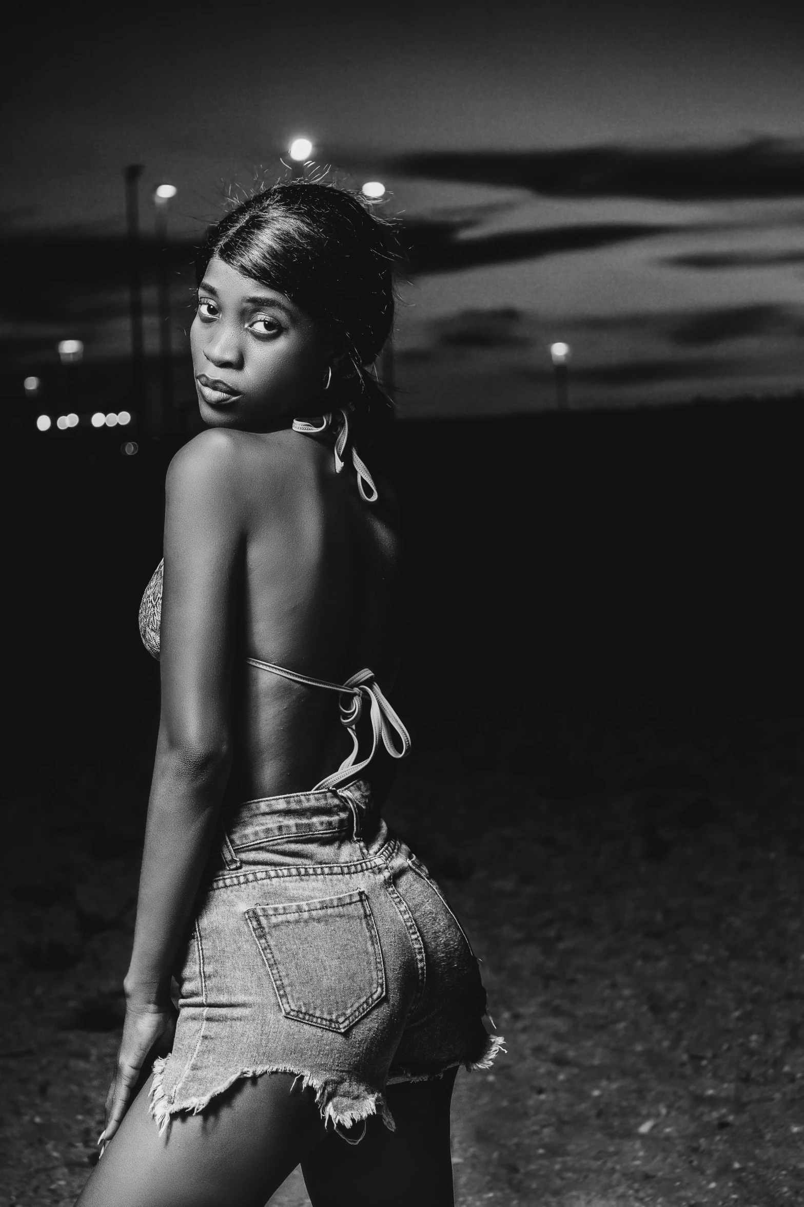 a black and white photo of a woman in shorts, a black and white photo, trending on pexels, sza, calm night. over shoulder shot, vanessa blue, toned derriere