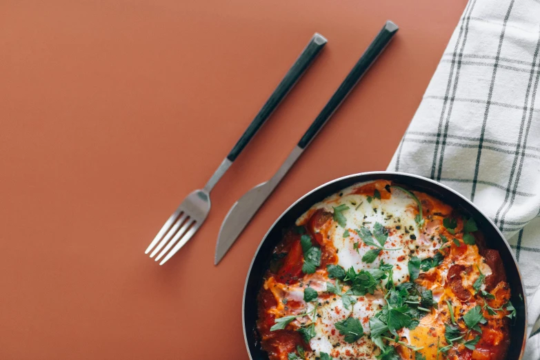 a pan of food sitting on top of a table, pexels contest winner, hurufiyya, spatula, background image, chilaquiles, minimalistic background