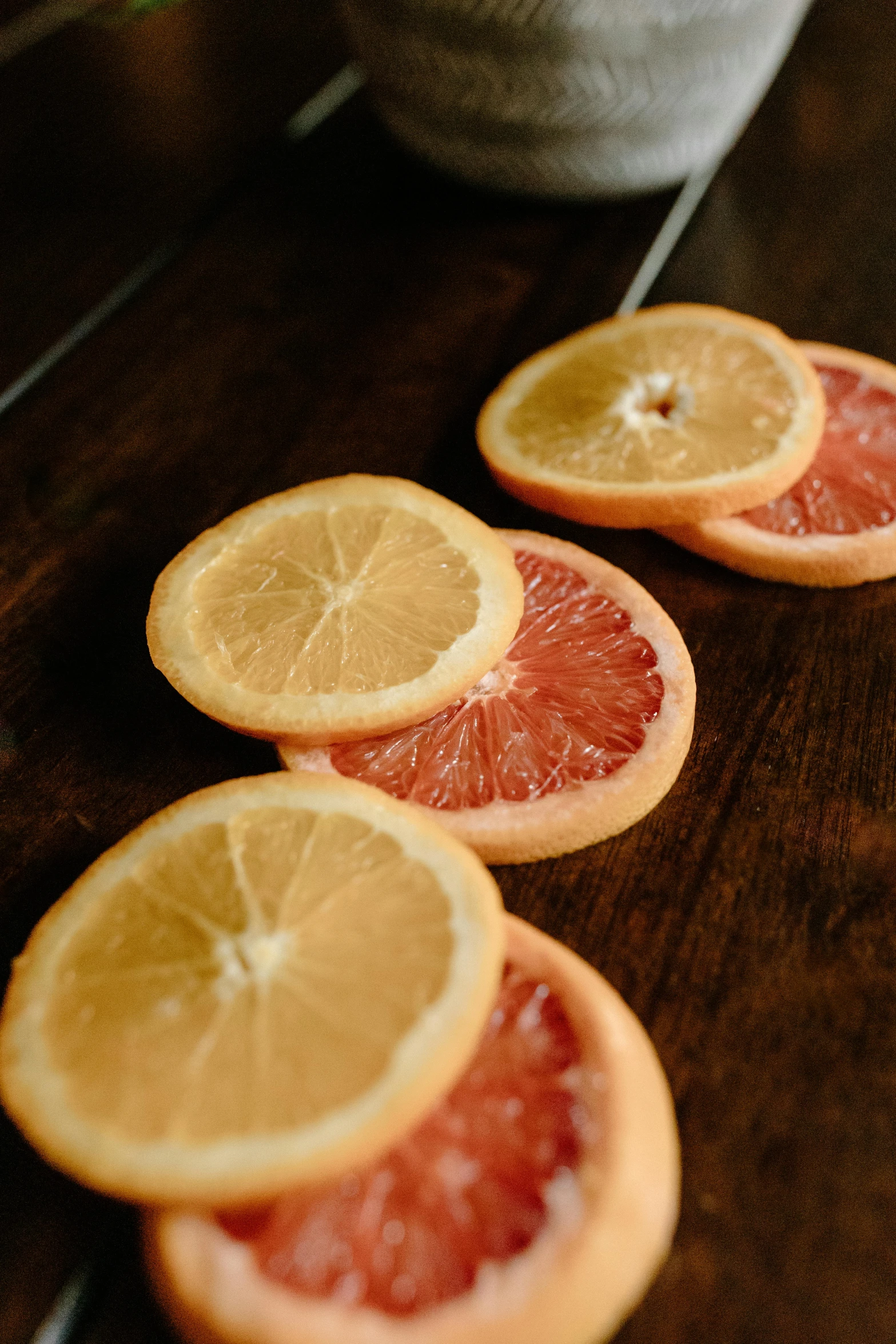 a wooden table topped with slices of grapefruit, 6 pack, dark oranges reds and yellows, hanging, upclose