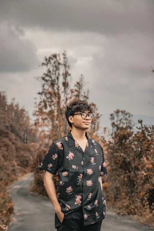 a man standing in the middle of a road, an album cover, pexels contest winner, sumatraism, wearing black frame glasses, amidst nature, he is about 20 years old | short, ((portrait))