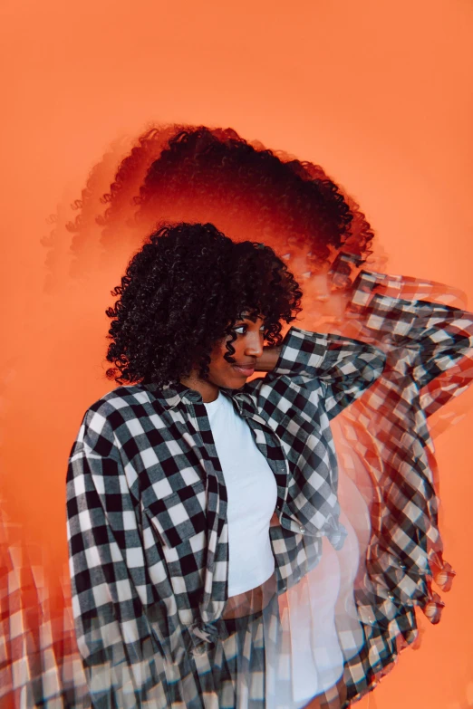 a woman standing in front of an orange background, trending on pexels, black arts movement, flannel, curls hair, desaturated, on white background