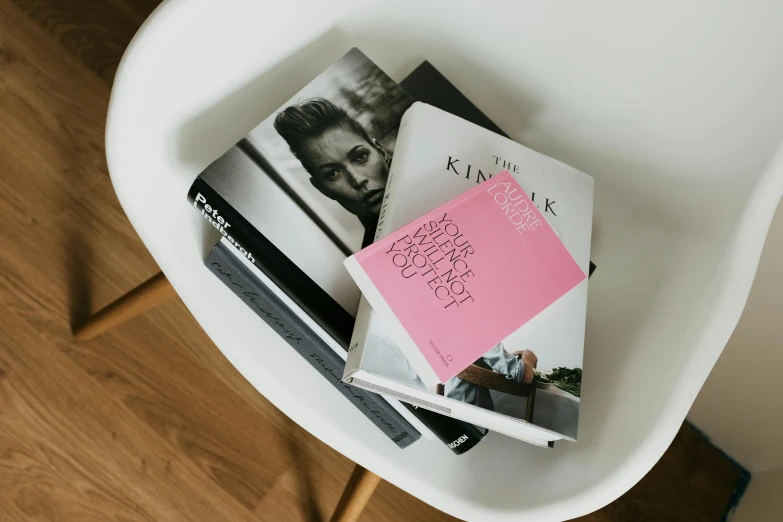 a stack of books sitting on top of a white chair, fashion magazines, exhibition catalogue, pink accents, portrait featured on unsplash