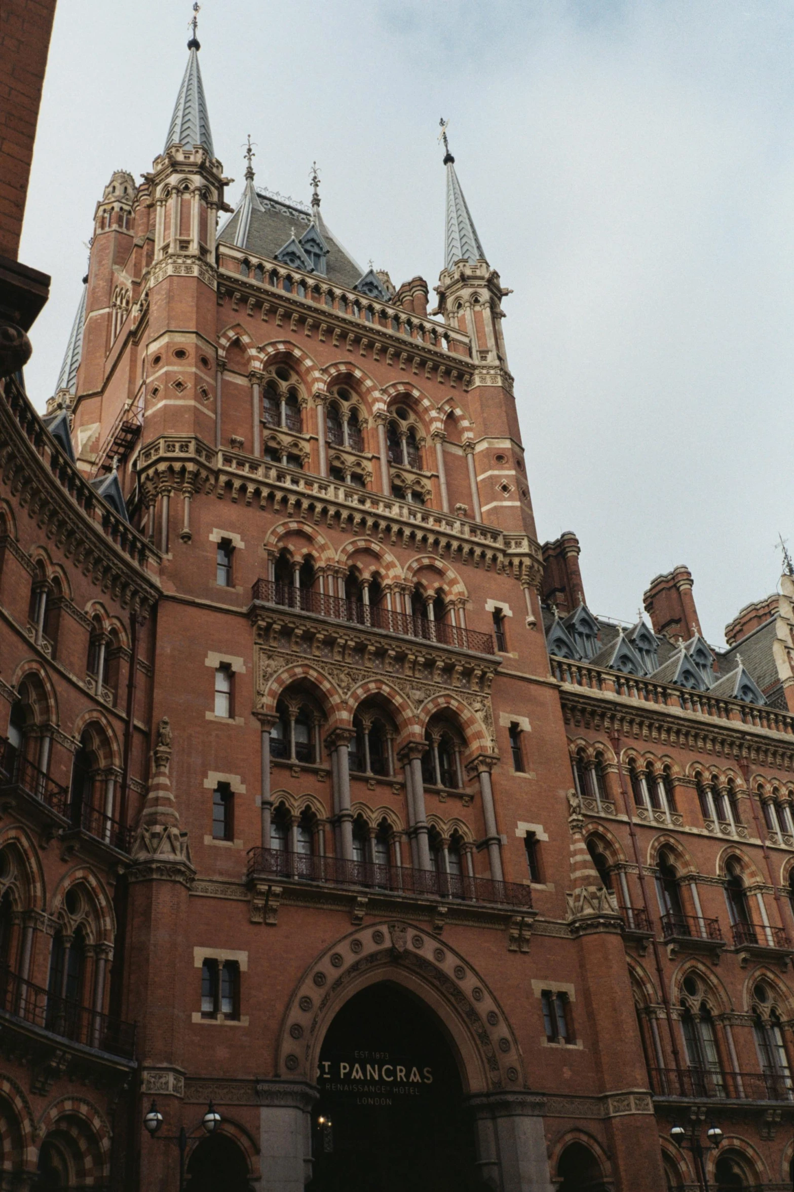 a tall building with a clock on top of it, inspired by William Mustart Lockhart, art nouveau, buttresses, brick building, college, exterior shot