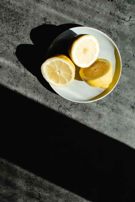 a plate of lemons sitting on a table, inspired by Arnold Newman, unsplash, back light, smooth surface, sun, snacks