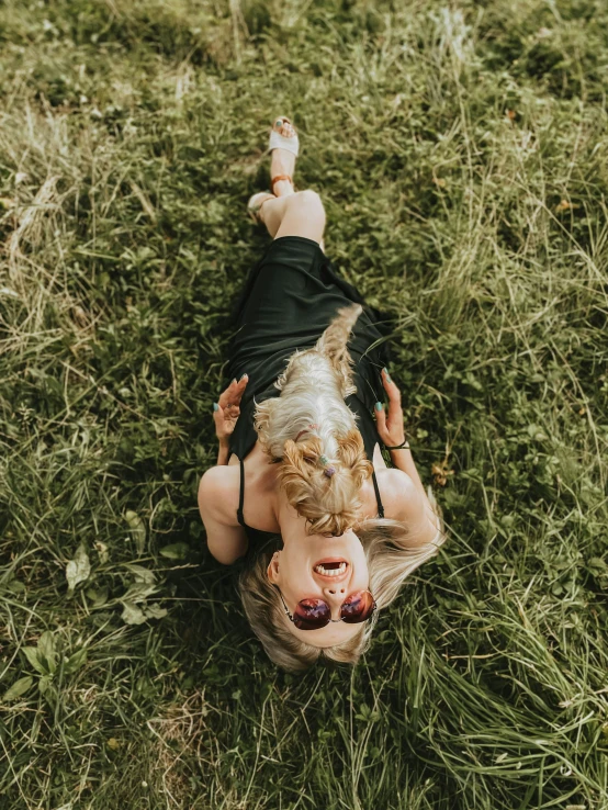 a woman laying in the grass with her dog, inspired by Elsa Bleda, pexels contest winner, doing a sassy pose, trending on vsco, she is wearing a black tank top, wide high angle view