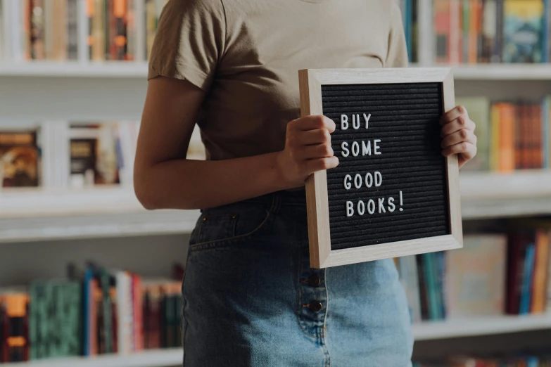 a woman holding a sign that says buy some good books, pexels contest winner, aestheticism, sustainable materials, instagram post, raphael lecoste, thumbnail