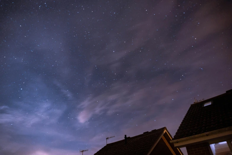 a couple of houses sitting next to each other under a night sky, by Andrew Allan, pexels contest winner, cloud nebula, star roof, altostratus clouds, looking partly to the left