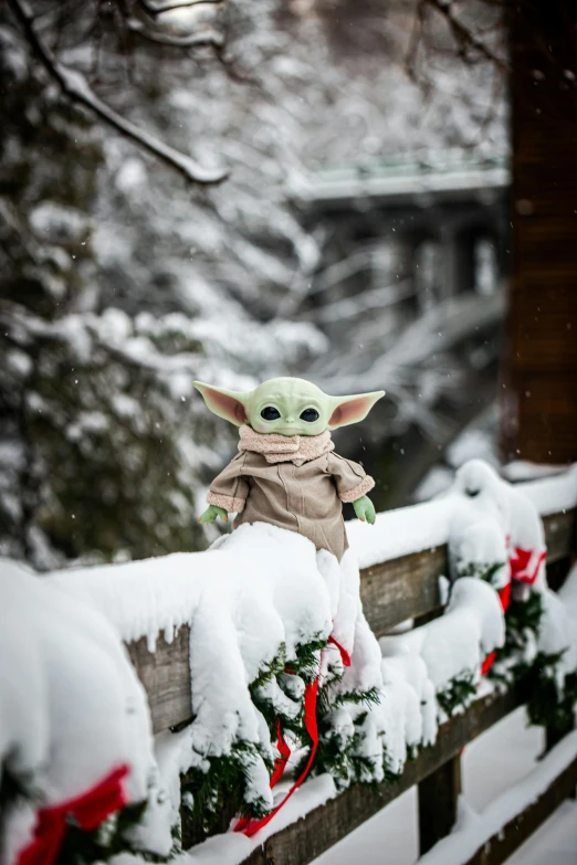 a baby yoda is sitting on a fence in the snow, a statue, ski masks, switzerland, elves house, slide show