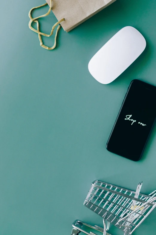 a laptop computer sitting on top of a desk next to a shopping cart, by Sven Erixson, trending on unsplash, minimalism, phone wallpaper. intricate, computer mouse, black and teal paper, corporate phone app icon