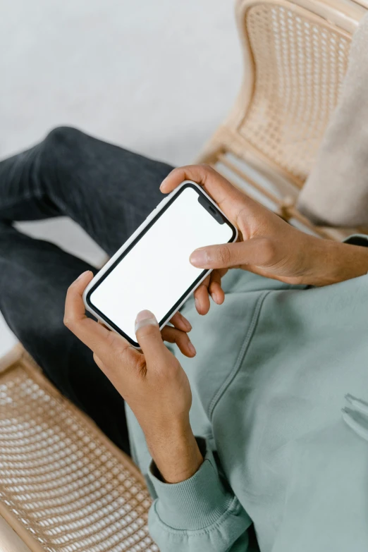 a man sitting on a chair holding a cell phone, trending on pexels, wearing a white sweater, flat lay, rectangle, uploaded
