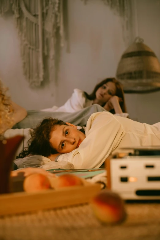 a couple of women laying on top of a bed, inspired by Nan Goldin, trending on pexels, happening, listening to music, cottagecore hippie, person in foreground, busy night