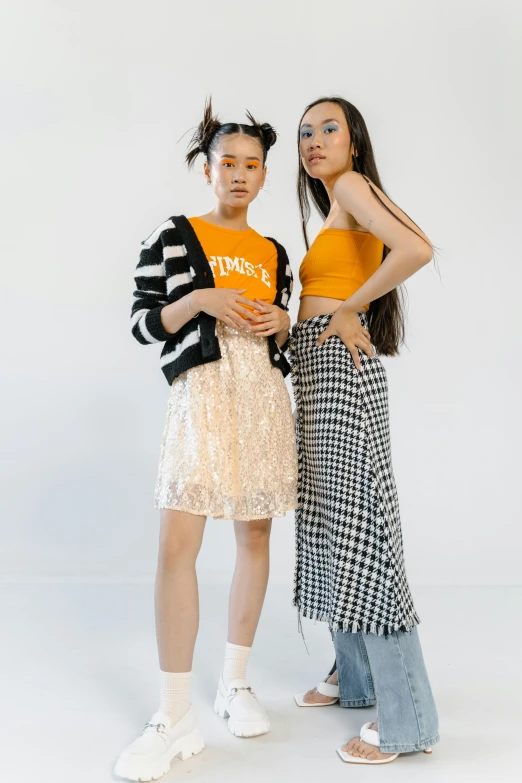 two young women standing next to each other, trending on unsplash, layered skirts, zeen chin and terada katsuya, orange and white, on a checkered floor