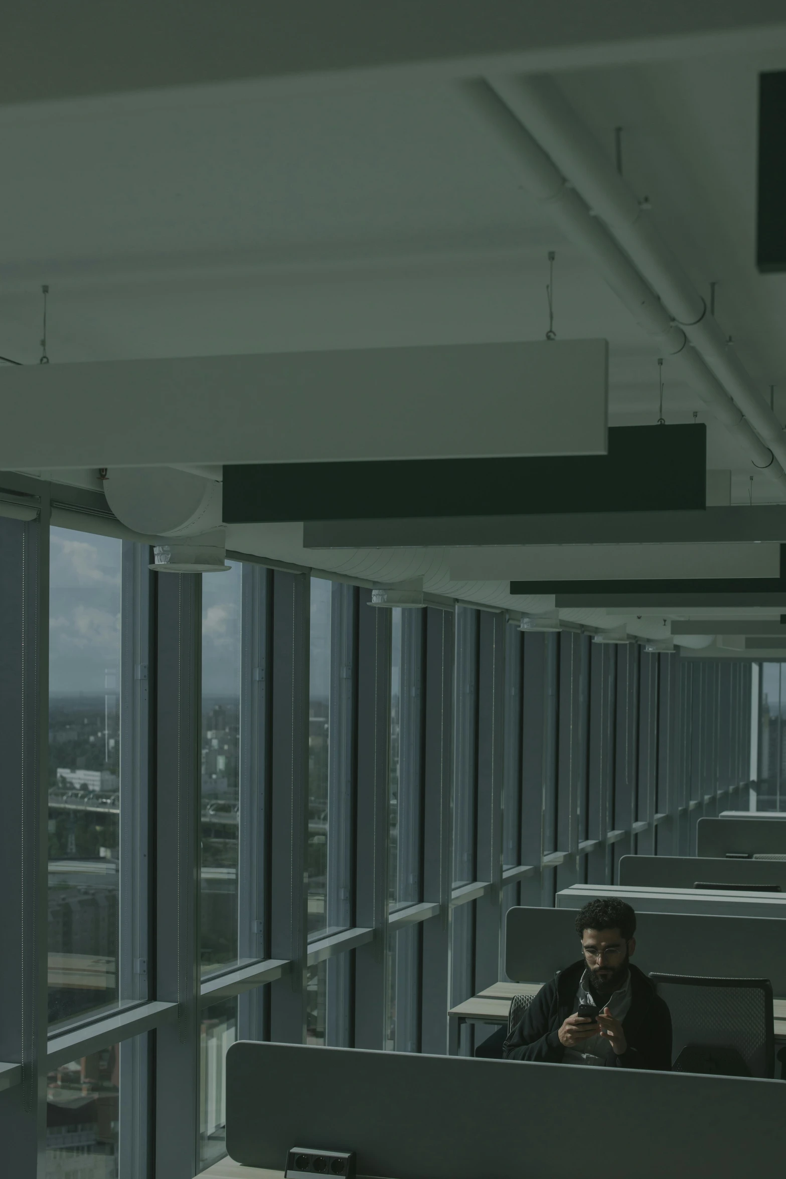 a man sitting at a desk in an office, inspired by Elsa Bleda, unsplash contest winner, modernism, sky made of ceiling panels, worksafe. cinematic, shot from roofline, in an call centre office