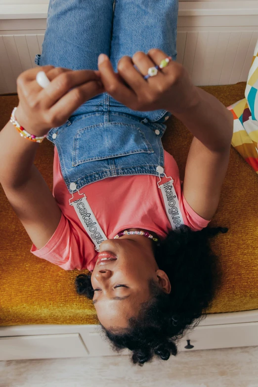 a close up of a person laying on a bench, colourful clothes, as she looks up at the ceiling, denim, cellphone