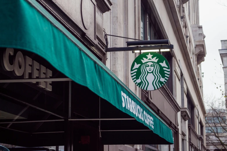 a starbucks sign hanging from the side of a building, trending on unsplash, renaissance, 🦩🪐🐞👩🏻🦳, awnings, discovered photo, seen from below