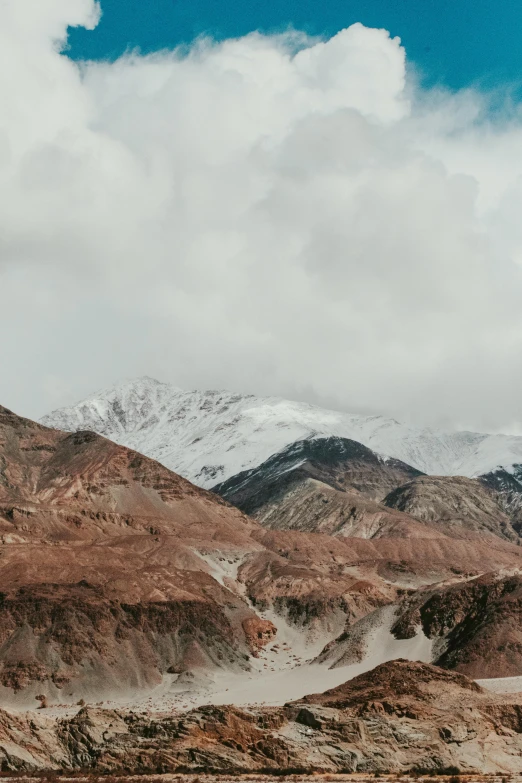 a man riding a motorcycle down a dirt road, a matte painting, by Muggur, trending on unsplash, snowy craggy sharp mountains, 4 k cinematic panoramic view, himalayas, earth and pastel colors