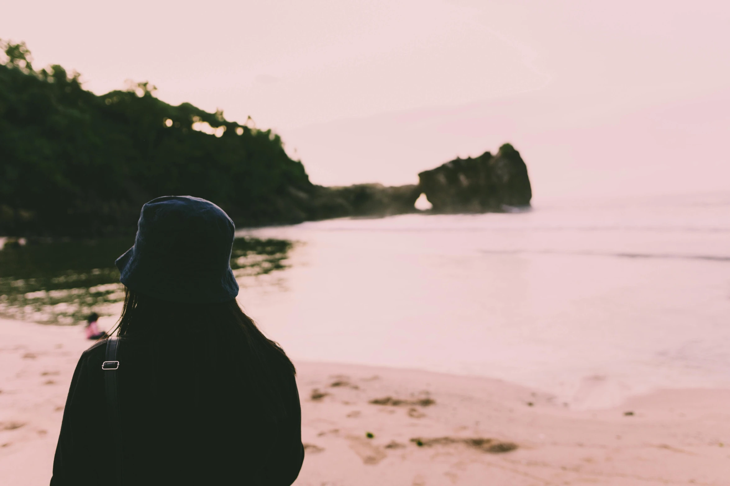 a person standing on a beach next to a body of water, unsplash, romanticism, wearing a purple cap, faded glow, pondering, panoramic view of girl