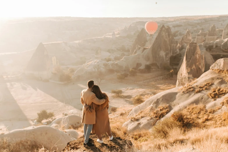 a man and a woman standing on top of a hill, pexels contest winner, romanticism, hot air balloon, hidden valley, youtube thumbnail, ash thorp khyzyl saleem