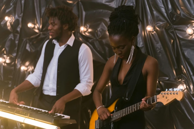 a couple of people that are playing a musical instrument, by Nele Zirnite, dark-skinned, band playing, high light on the left, backdrop