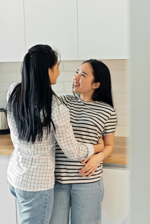 a couple of women standing next to each other in a kitchen, inspired by Ruth Jên, pexels contest winner, happening, membrane pregnancy sac, young asian woman, facing each other, soft lulling tongue