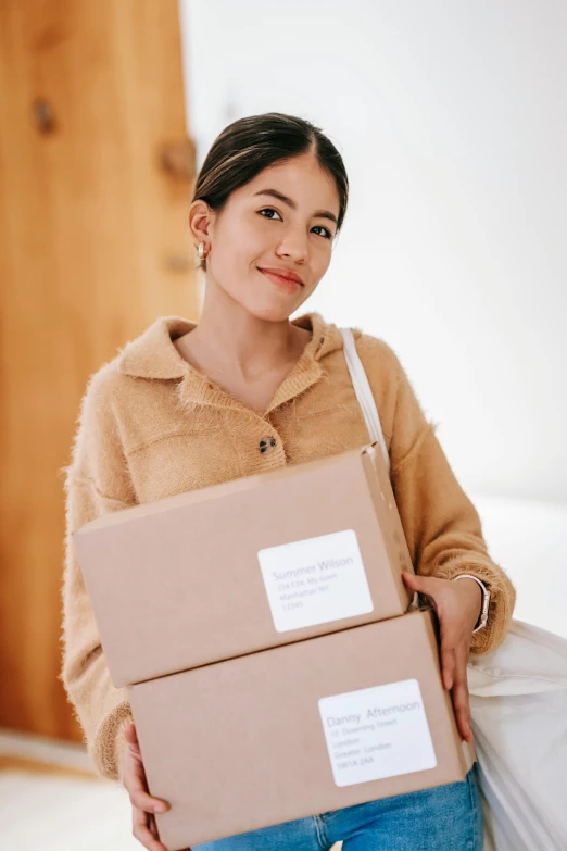 a woman holding two boxes in her hands, pexels contest winner, portrait of modern darna, customer, long sleeves, promo image