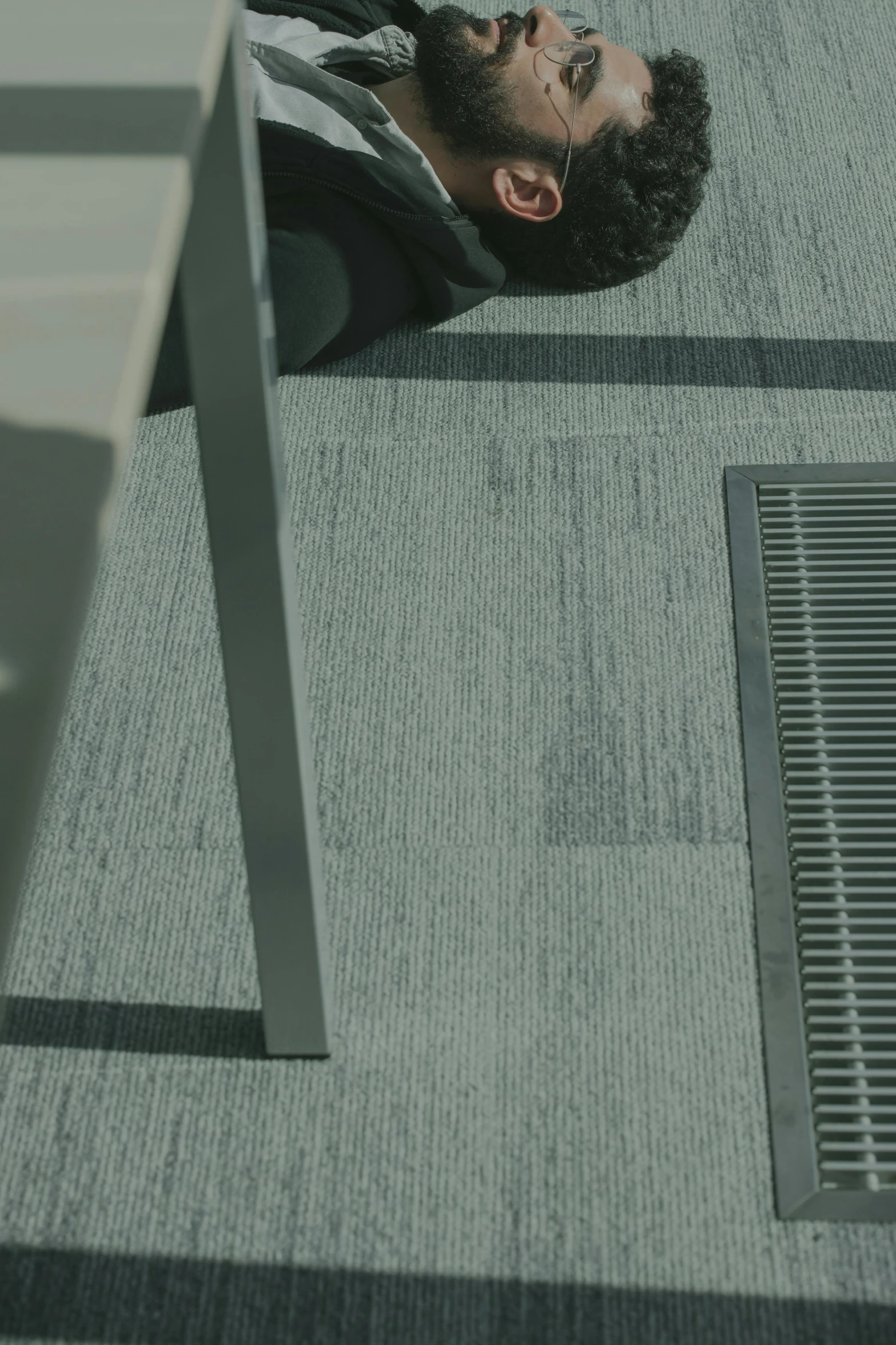 a man laying on the ground next to a table, unsplash, textured like a carpet, standing on rooftop, detail shot, vents