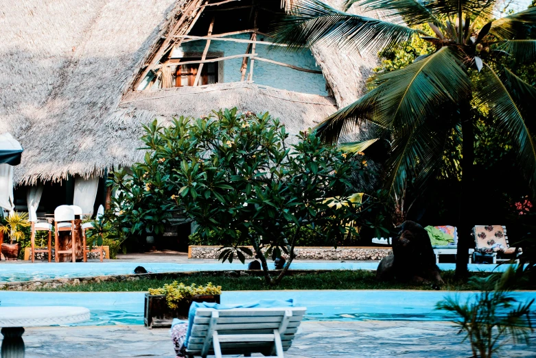 a house with a thatched roof next to a pool, unsplash, visual art, mami wata, 1980s photo, fan favorite, holiday resort