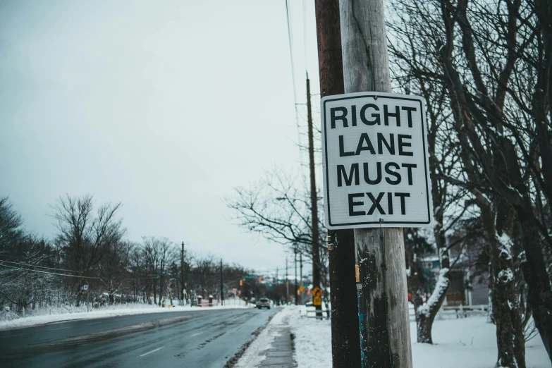 a right lane must exit sign on a telephone pole, a photo, trending on pexels, visual art, winter vibes, waist high, street corner, ansel ]