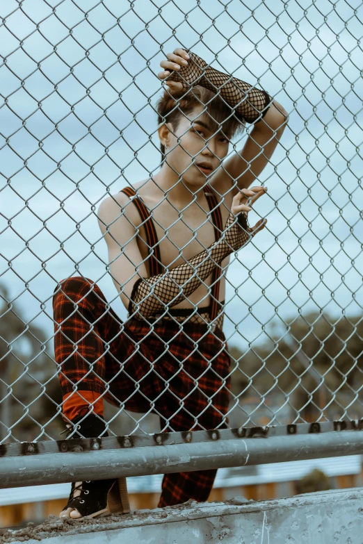 a woman sitting in front of a chain link fence, by Byron Galvez, trending on pexels, attractive androgynous humanoid, in an action pose, asian man, ashteroth
