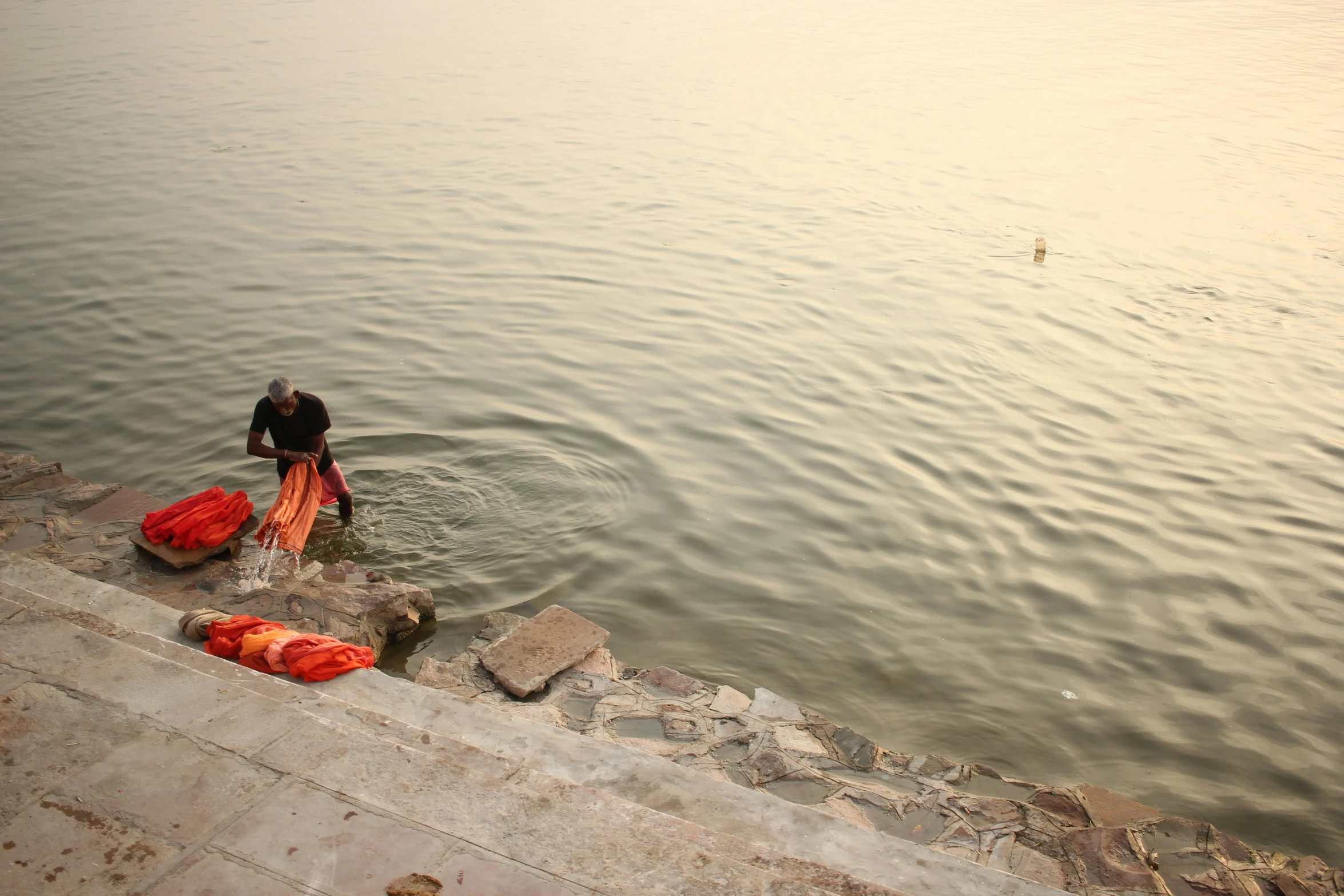 a person standing in the water near a body of water, happening, kalighat, sweeping vista, ignant, clothes floating