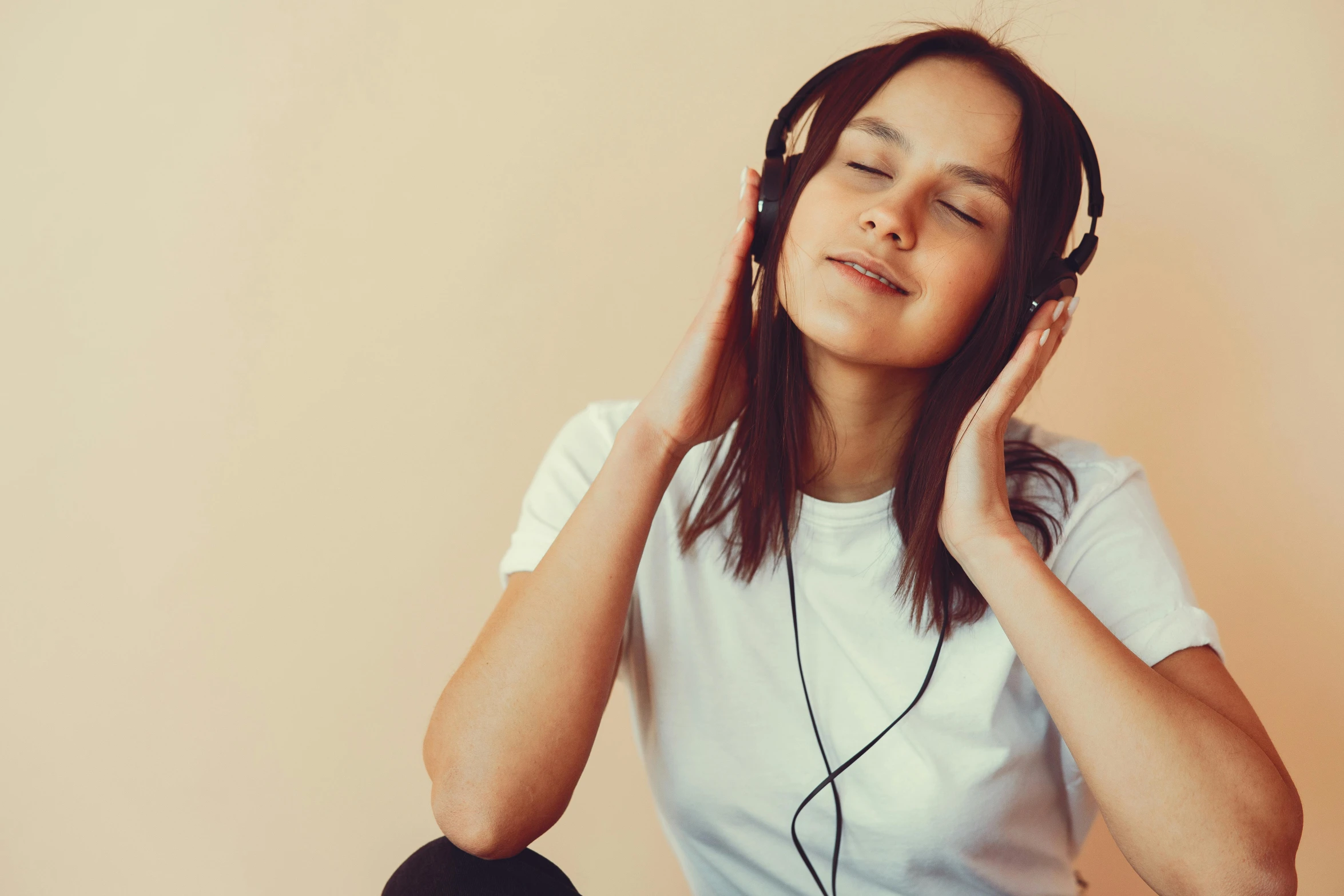 a woman is listening to music with headphones, inspired by Ella Guru, trending on pexels, aestheticism, on a pale background, sitting down, instagram photo, relaxed. gold background