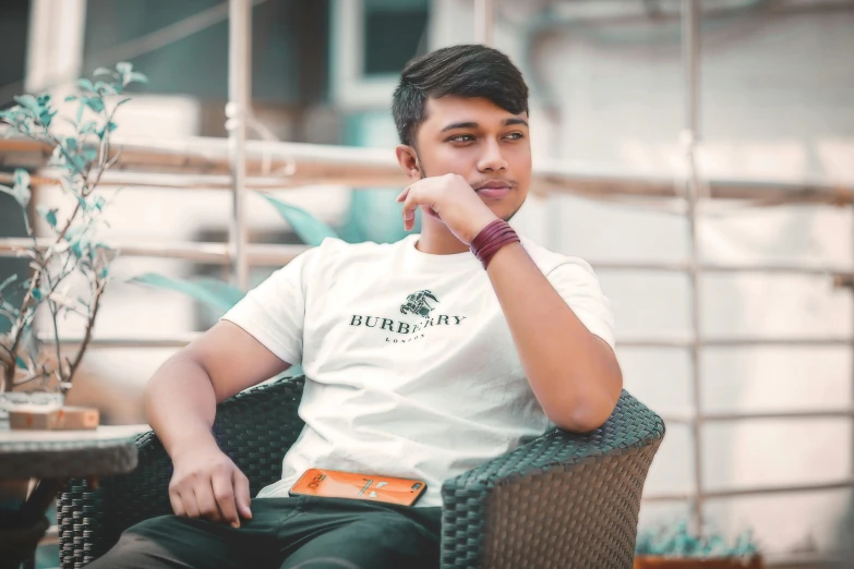 a man sitting in a chair with his hand on his chin, inspired by Saurabh Jethani, pexels contest winner, hurufiyya, wearing a t-shirt, male teenager, slightly tanned, avatar image