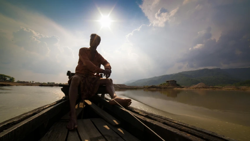a man sitting on top of a wooden boat, inspired by Steve McCurry, pexels contest winner, sumatraism, blinding sun, anthropology photo”, album cover, myanmar