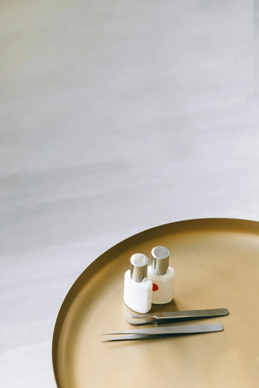 a pair of scissors sitting on top of a table, a still life, inspired by Agnes Martin, minimalism, round-cropped, liquid gold, salt shaker, brushed metal