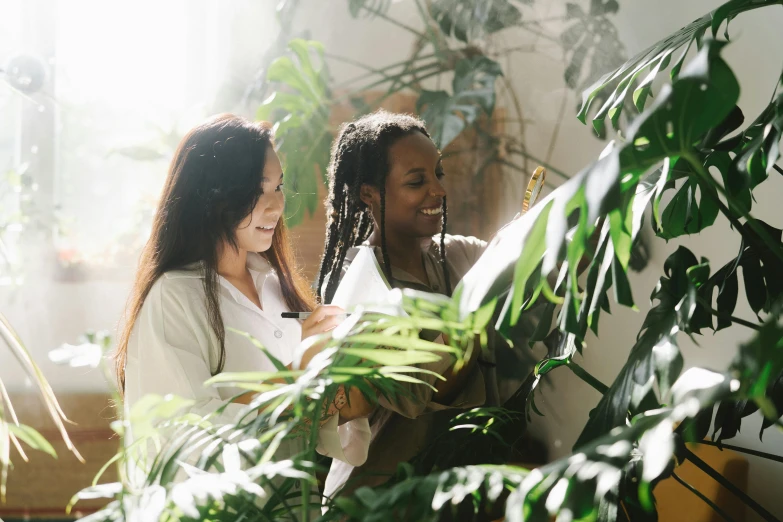 a couple of women standing next to each other near a plant, pexels contest winner, studying in a brightly lit room, avatar image, green jungle, profile image
