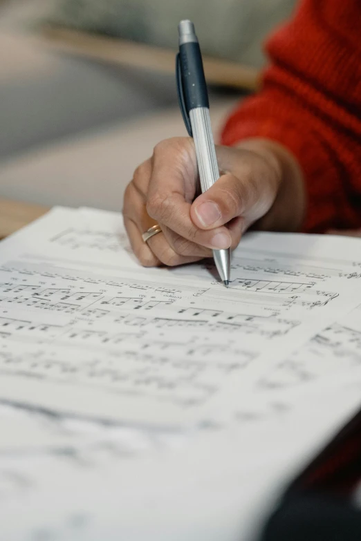 a person writing on a piece of paper with a pen, an album cover, by Glennray Tutor, pexels, precisionism, sheet music, paul barson, sandra pelser, performance