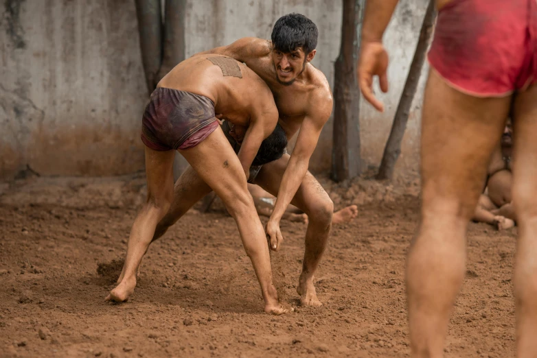 a couple of men playing a game of wrestling, an album cover, pexels contest winner, indian, dirty and sweaty, standing in an arena, hard clay