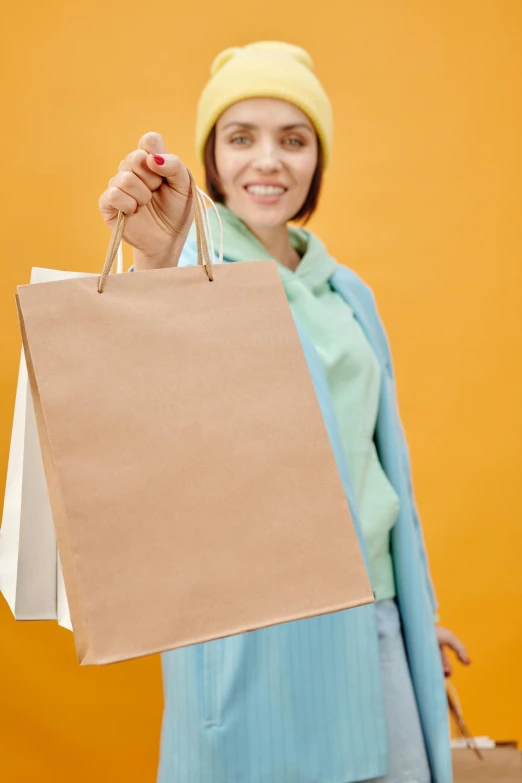 a woman holding shopping bags and smiling at the camera, shutterstock contest winner, renaissance, yellow hue, thumbnail, small, cardboard