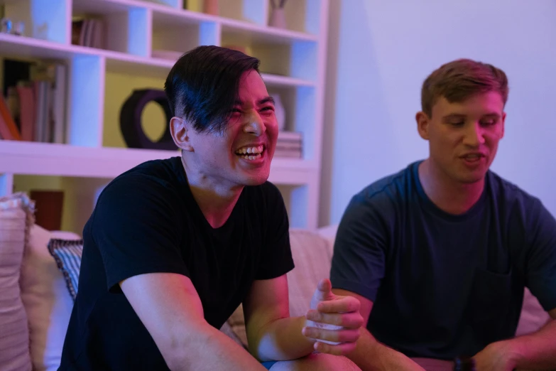 two men sitting on a couch playing a video game, reddit, edgar maxence and ross tran, smiling laughing, promo image, colour photograph