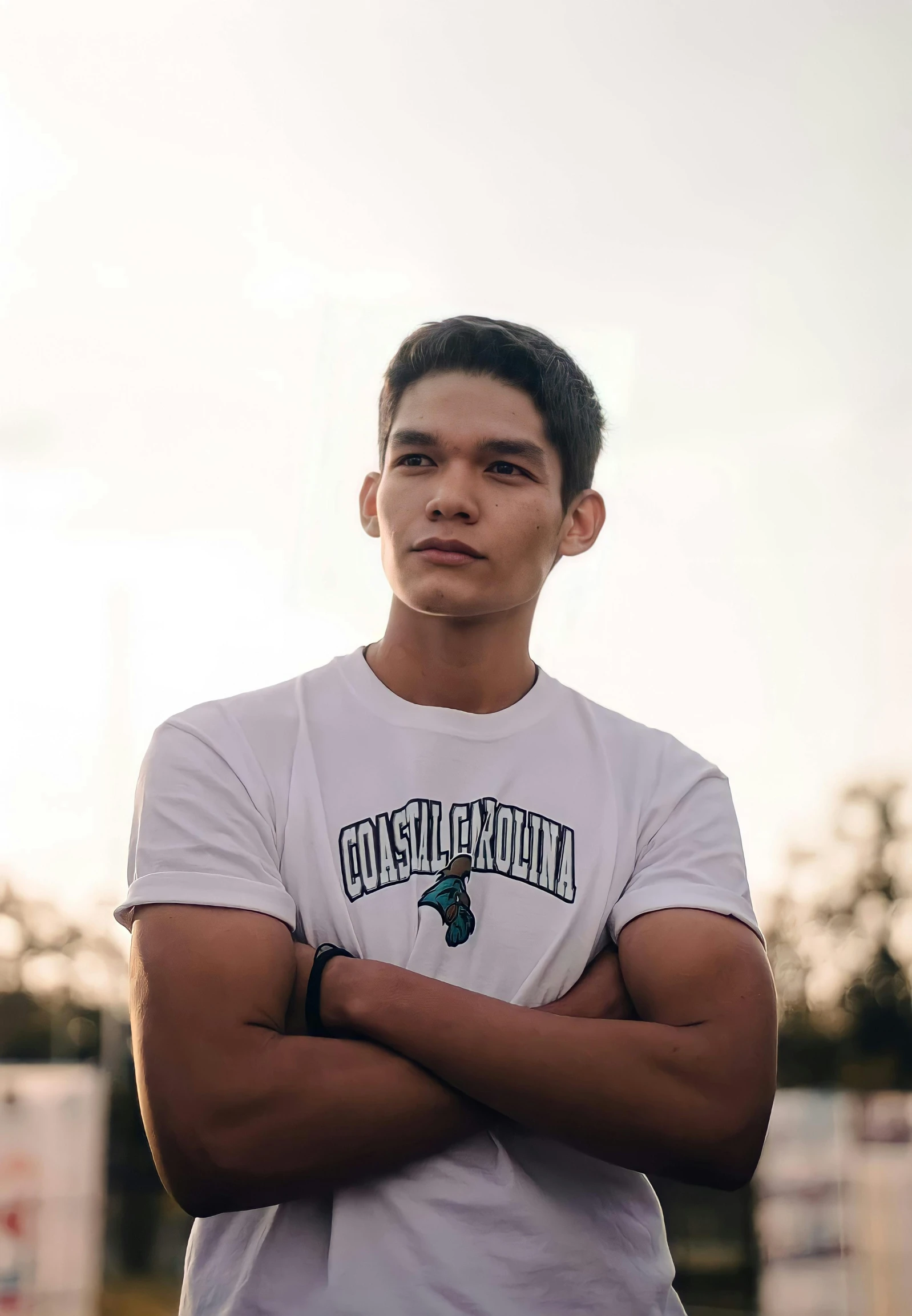 a man standing in a field with his arms crossed, featured on instagram, tan skin a tee shirt and shorts, ramil sunga, headshot profile picture, he is about 20 years old | short