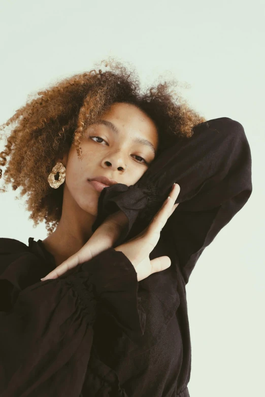 a woman with curly hair posing for a picture, trending on pexels, renaissance, casual black clothing, androgyny, giant earrings, hands behind her pose!