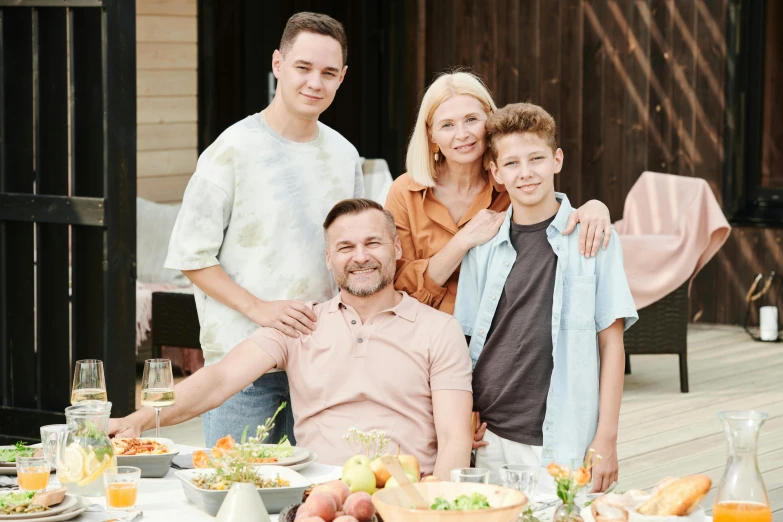 a family posing for a picture in front of a table full of food, a portrait, by Zofia Stryjenska, pexels contest winner, attractive man, matt colors outdoor, 15081959 21121991 01012000 4k, hd footage