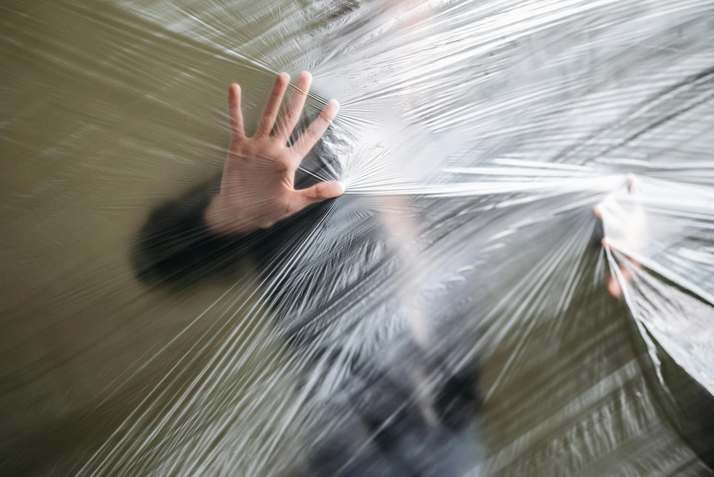 a close up of a person holding an umbrella, inspired by Cornelia Parker, unsplash, plasticien, plastic wrap, motion lines, containment pod, hands shielding face