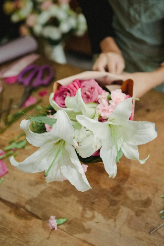 a person cutting flowers with a pair of scissors, lillies, white and pink, professionally done, bustling