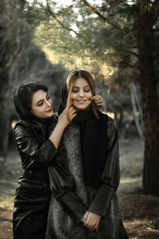 two women standing next to each other in a forest, by irakli nadar, trending on pexels, romanticism, black scarf, iranian, leather, elegant smiling pose