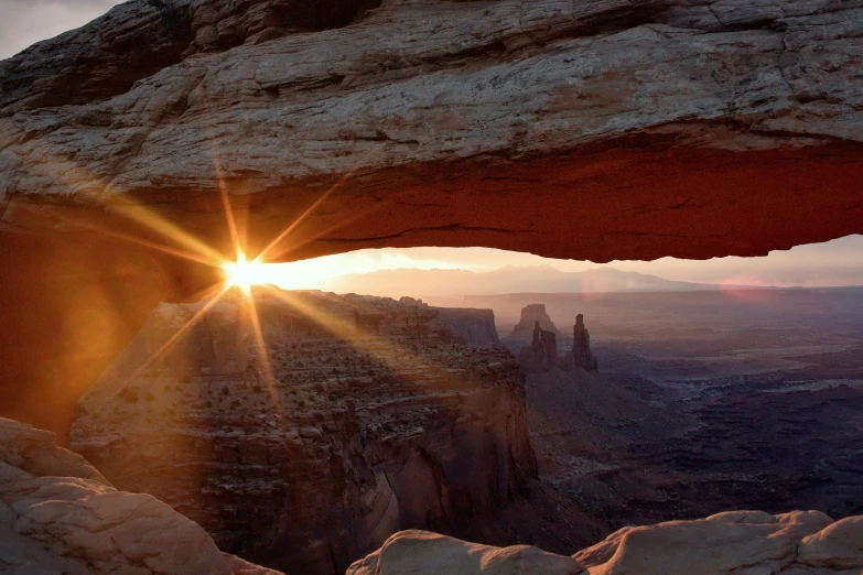 the sun shines through an arch in the desert, a picture, unsplash contest winner, hudson river school, buildings carved out of stone, mesa plateau, taken in the early 2020s, the sun reflecting on a window