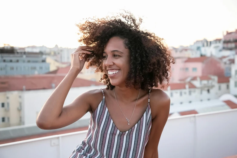 a beautiful young woman standing on top of a roof, pexels contest winner, happening, curly middle part haircut, smiling coy, ( brown skin ), instagram post