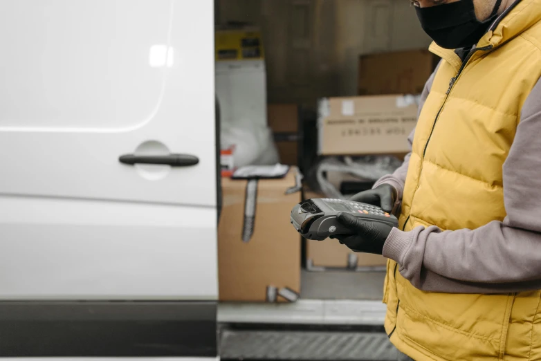 a man in a yellow vest standing next to a white van, pexels contest winner, wearing gloves, avatar image, inspect in inventory image, holding controller